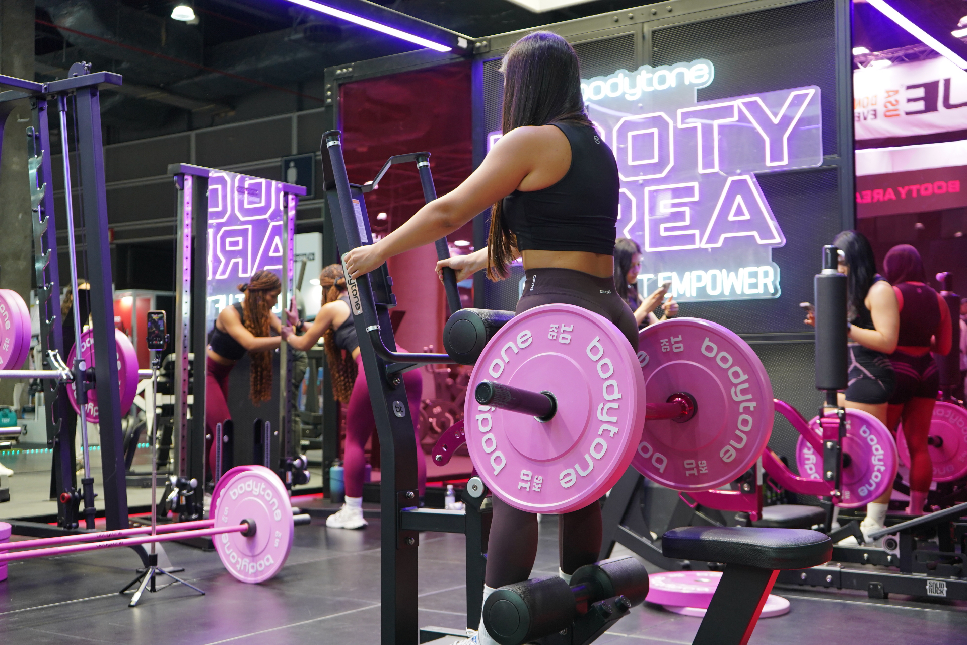 Socia entrenando en la Booty Area de Bodytone rodeada de neón